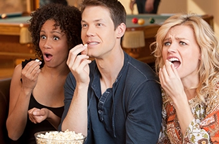 Three adults eating popcorn