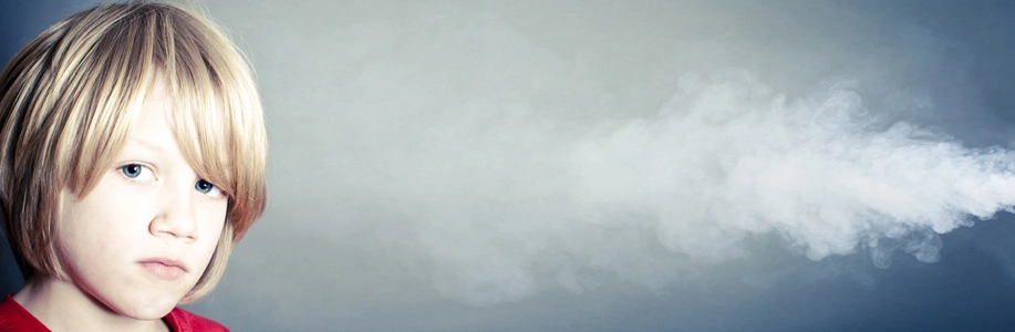 Young boy looks directly at camera while smoke swirls around his head