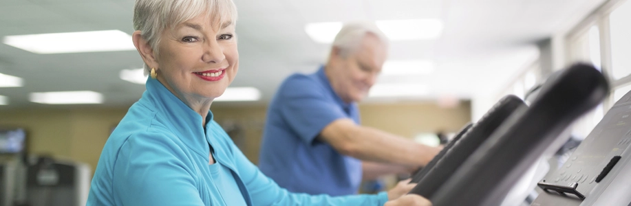 Older woman smiles at camera while exercising at gym